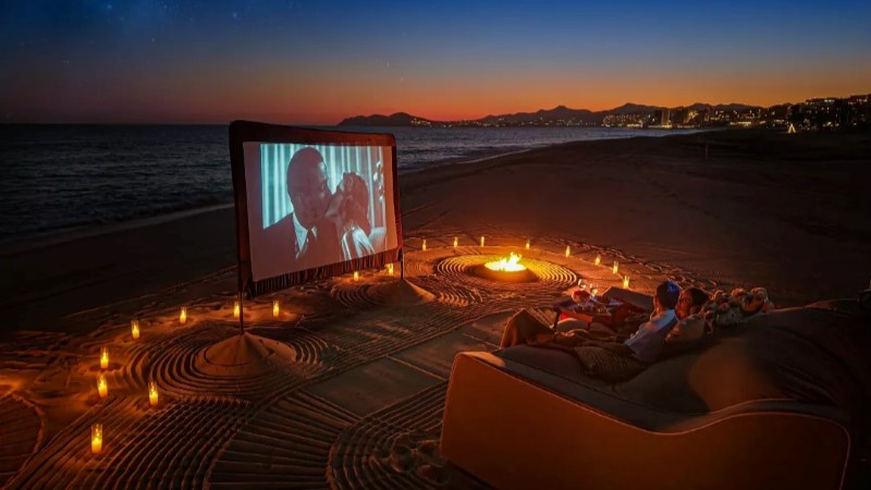 Casal assistindo filme na praia à noite no Las Ventanas al Paraíso