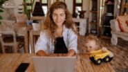 Mãe trabalhando no notebook enquanto a filho observa em ambiente familiar acolhedor