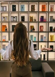 Pessoa observando uma prateleira repleta de perfumes em referência ao burnout olfativo e excesso de estímulos na perfumaria