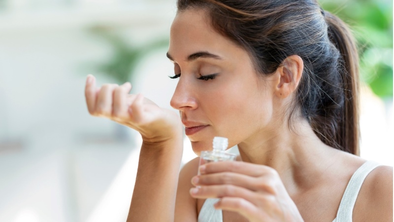 Mulher sentindo um perfume no braço em conexão com memória olfativa e emoção