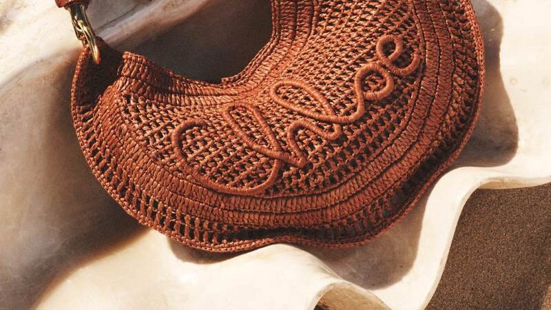 Bolsa marrom da coleção Chloé à la Plage 2026 posicionada sobre concha em composição editorial