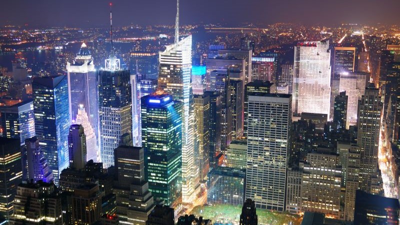 Vista aérea noturna de um centro financeiro internacional representando crescimento econômico, valor empresarial e mercado corporativo