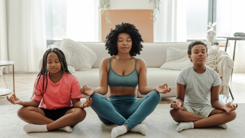 Mãe e filhos praticando yoga simbolizando parentalidade positiva e saúde emocional da família