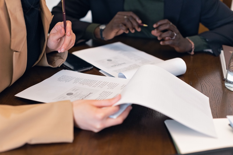 Duas pessoas analisam papéis com gráficos sobre uma mesa de reunião