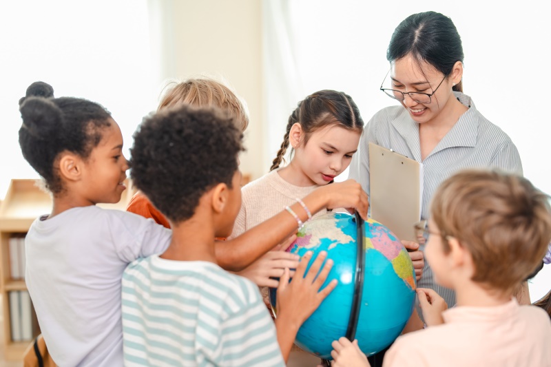 Professora e jovens estudantes explorando um globo terrestre
