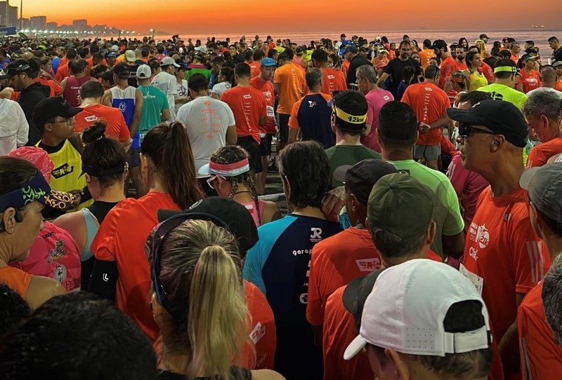 Grupo de corredores reunidos em uma praia antes de uma prova