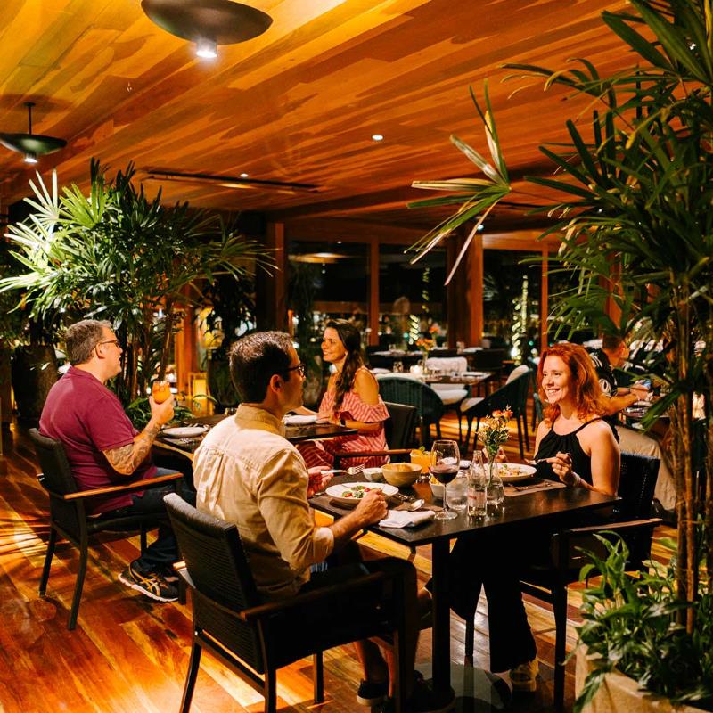 Ambiente interno do THE JUL’S com hóspedes e revestimentos em madeira