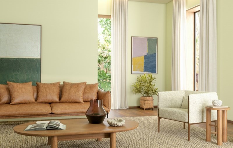 Sala com paredes na cor Aipo, sofá marrom, poltrona e mesa de centro