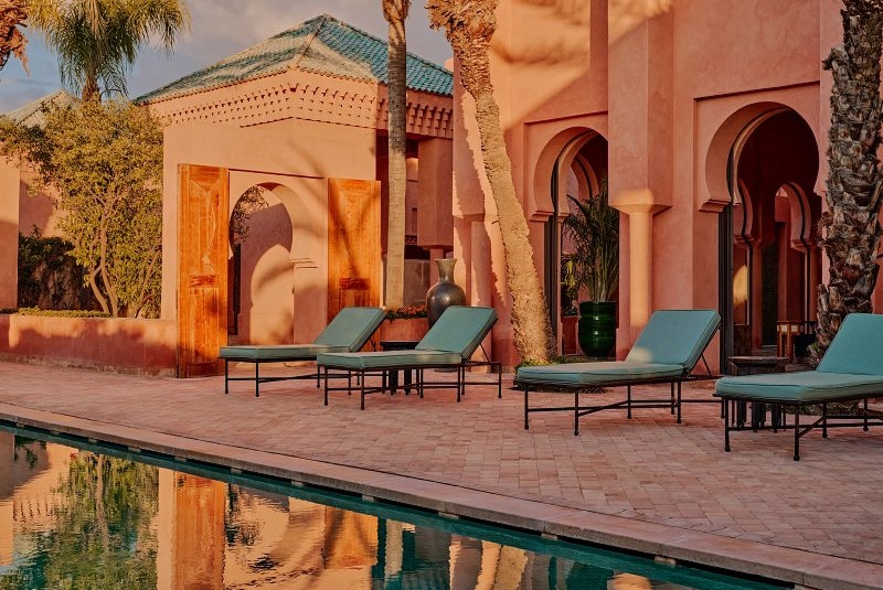 Piscina do Amanjena com espreguiçadeiras e arquitetura ao fundo