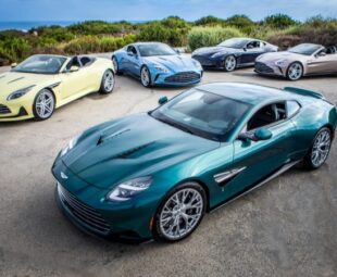 Cinco modelos Aston Martin Heritage Edition em estrada próxima ao mar