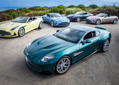 Cinco modelos Aston Martin Heritage Edition em estrada próxima ao mar