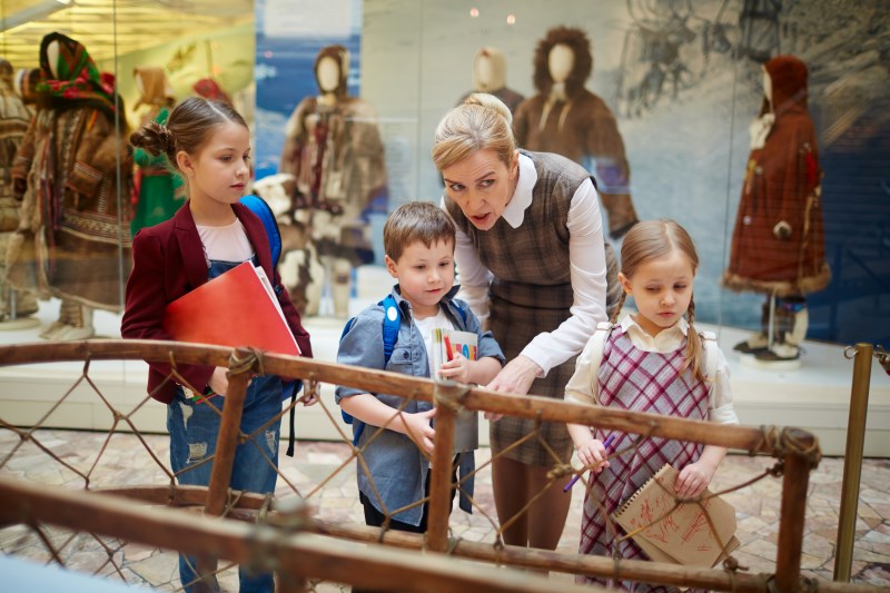 Crianças aprendendo com um adulto em um museu de ciência