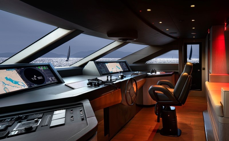 Ponte de comando do Custom Line 140 com cadeira, vidros frontais e controles de navegação