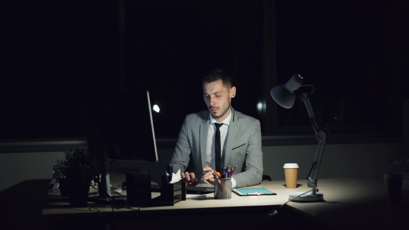Falta de Riqueza e qualidade de vida faz Executivo de terno trabalhando à noite em uma mesa iluminada