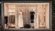 Vitrine de uma boutique de luxo com dois vestidos de festa e elementos de mármore ao fundo