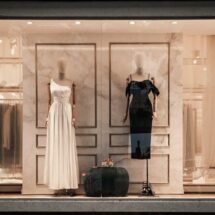 Vitrine de uma boutique de luxo com dois vestidos de festa e elementos de mármore ao fundo