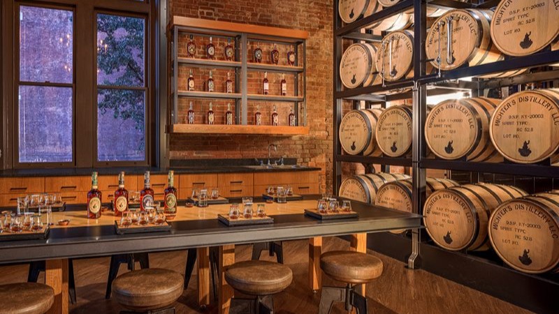 Interior da destilaria Michter's com barris de uísque armazenados e garrafa sobre uma mesa