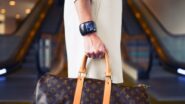 Mulher de branco usando relógio de pulso e segurando bolsa Louis Vuitton