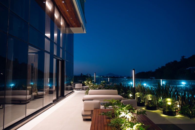 Área externa do Vista Mare ao entardecer com terraço e iluminação