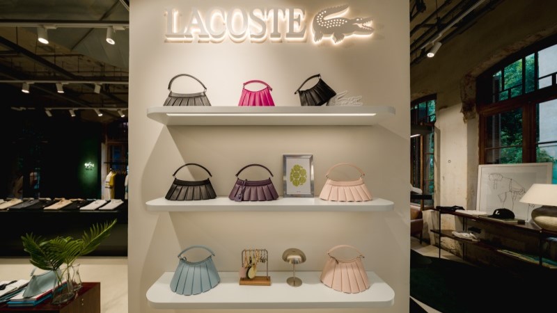 Bolsas Lacoste em expositor branco na Mata Lab
