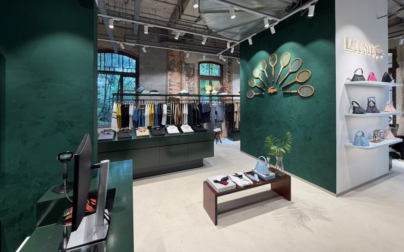 Caixa da loja Lacoste com expositores de roupas, tênis e bolsas