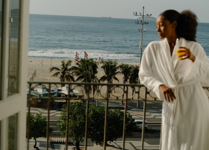 Mulher de roupão branco diante da praia