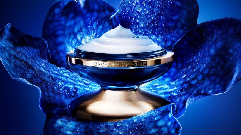 Embalagem em formato de pote do produto Guerlain Orchidée Impériale sobre fundo azul