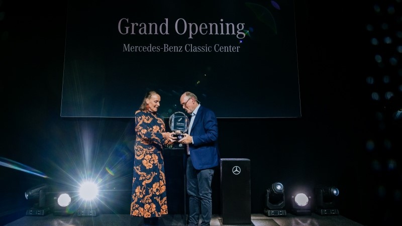 Homem e mulher no palco segurando um troféu durante uma cerimônia