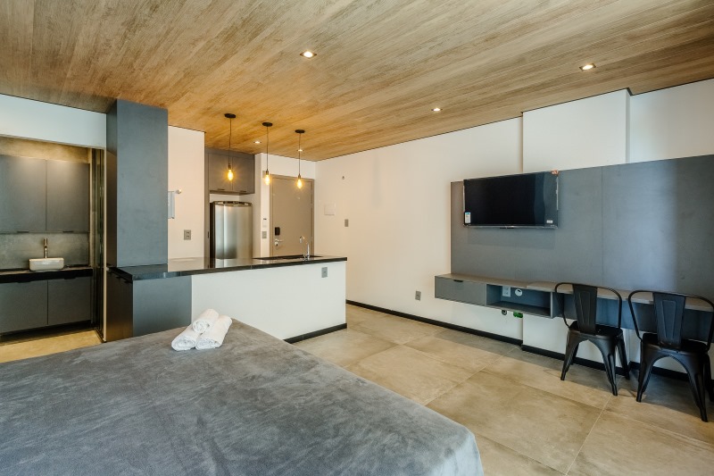 Área interna do apartamento New Time com cama e espaço para refeições