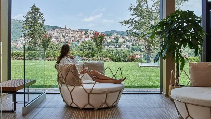 Mulher sentada em uma poltrona de descanso, contemplando a paisagem em um ambiente do Palazzo Fiuggi