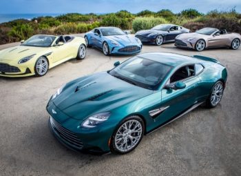 Cinco modelos Aston Martin Heritage Edition em estrada próxima ao mar