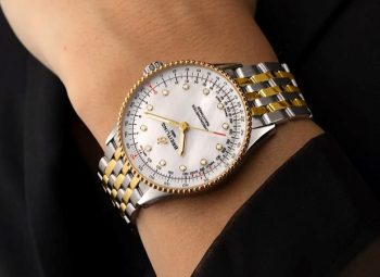 Relógio Breitling com detalhes em ouro amarelo e pulseira metálica no pulso