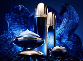 Produtos Guerlain Orchidée Impériale Concentrado da Longevidade em diferentes embalagens, sobre fundo azul